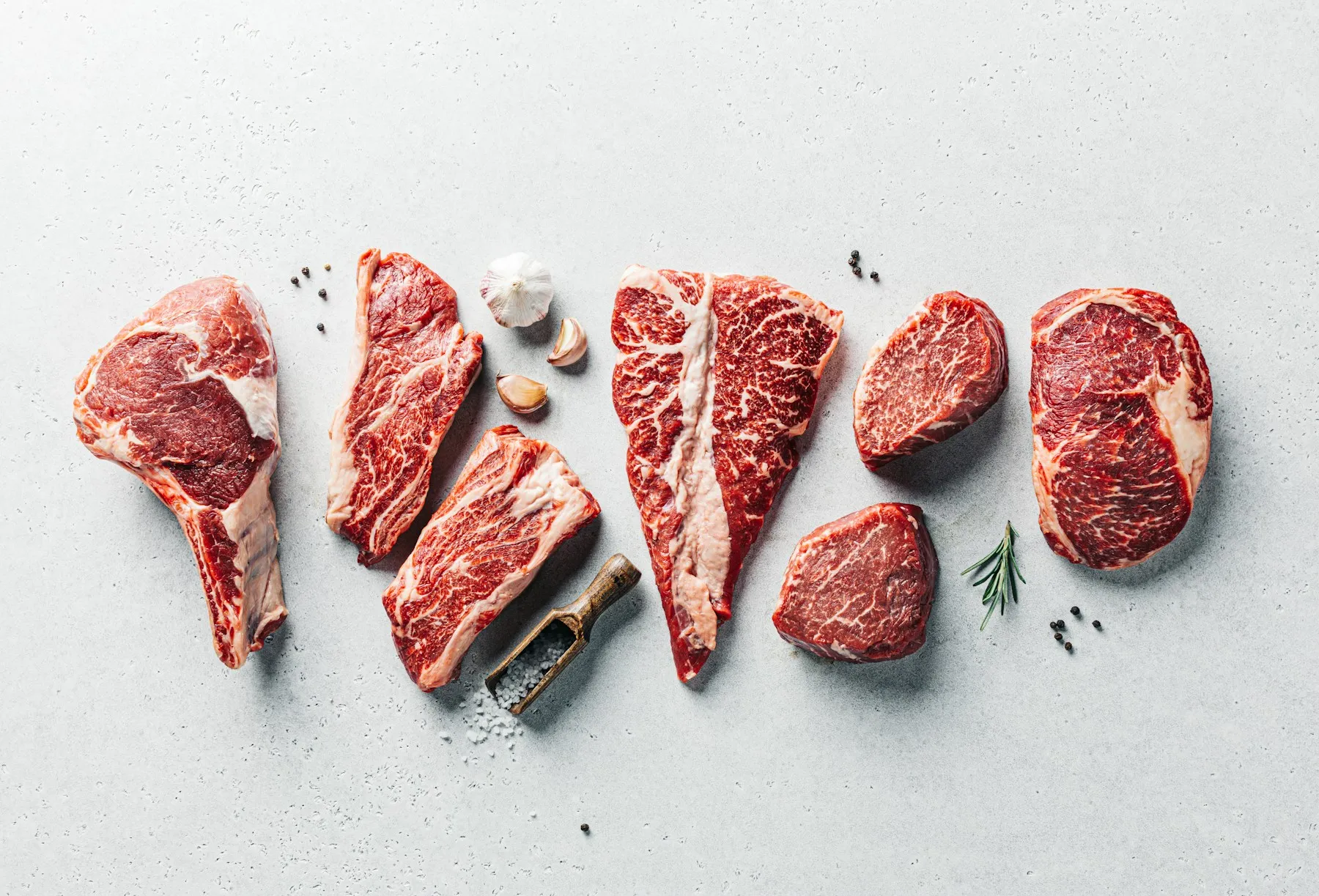 Verschiedene rohe Rindfleisch-Zuschnitte auf hellem Untergrund