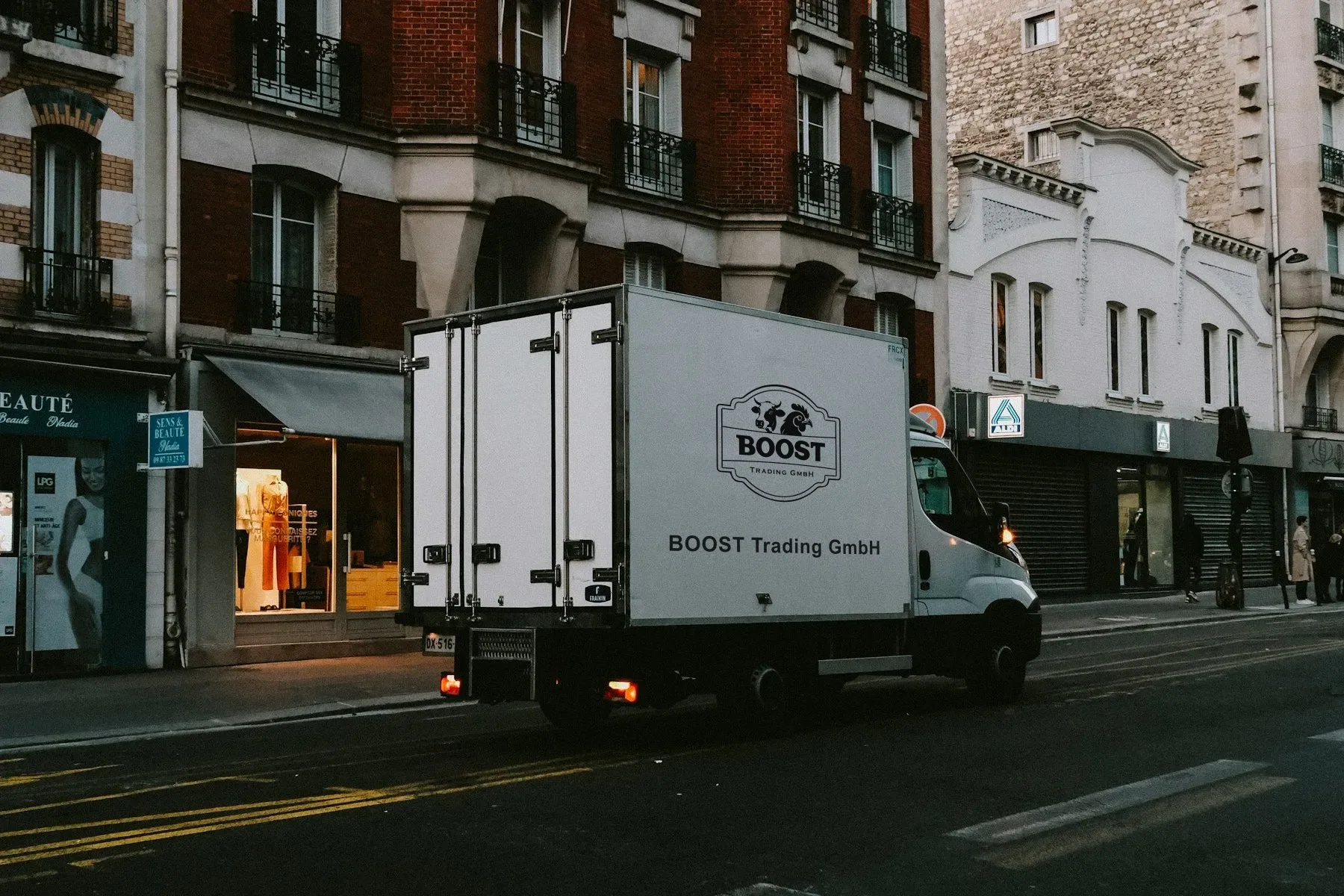 Weißer Kühl-Lieferwagen mit BOOST-Logo unterwegs in einer Stadtstraße